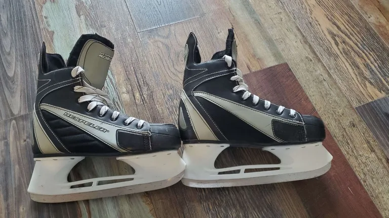 Patins de hockey Hespeler Rogue noirs et blancs, taille adulte, posés sur plancher en bois à Montréal Plateau